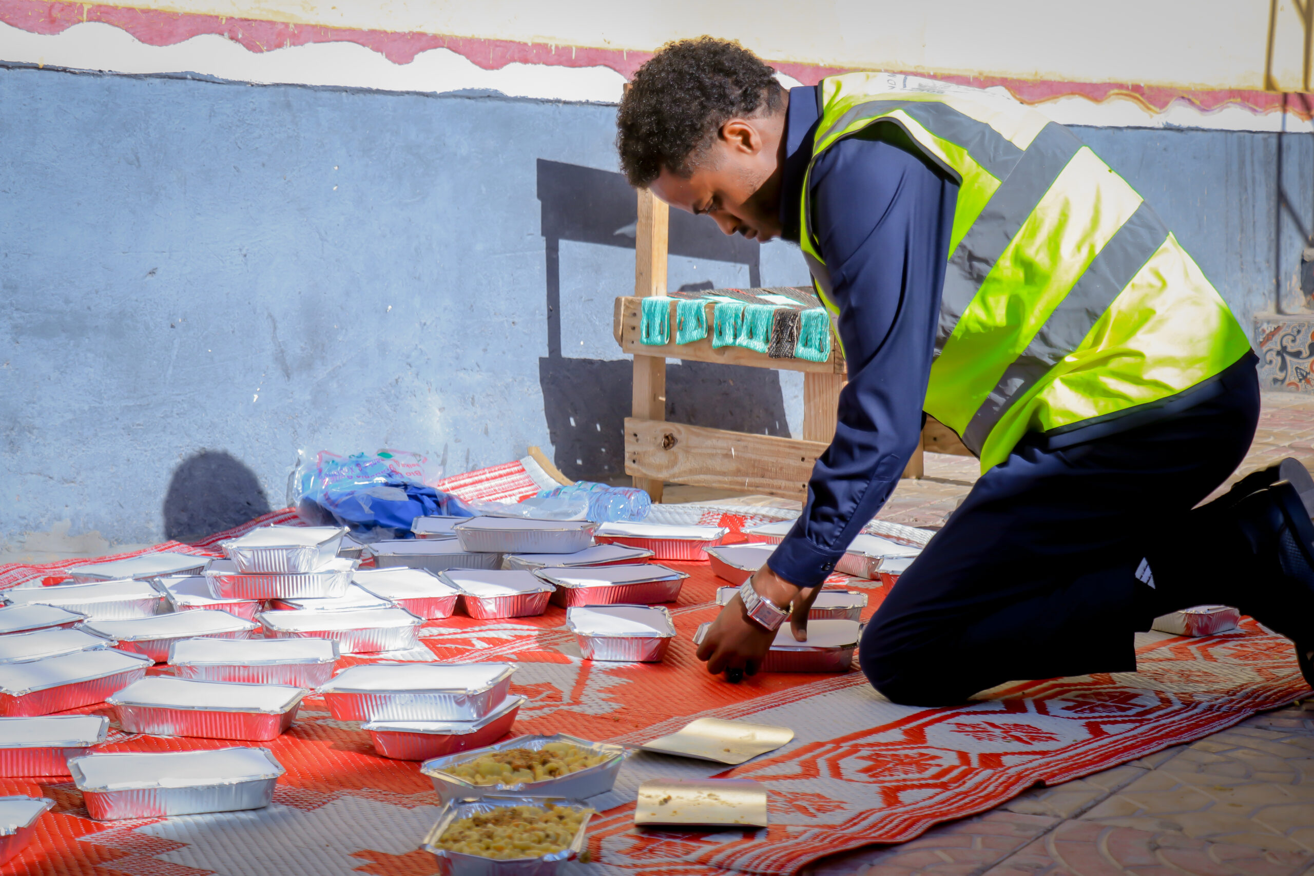 A volunteer arranging prepared meals in foil containers.